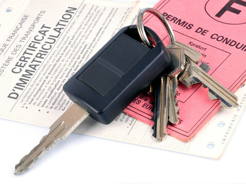 clés de voiture sur un permis de conduire et un certificat d'immatriculation
