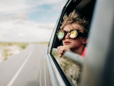 Petit garçon regardant par la fenêtre d'une voiture avec des lunettes de soleil