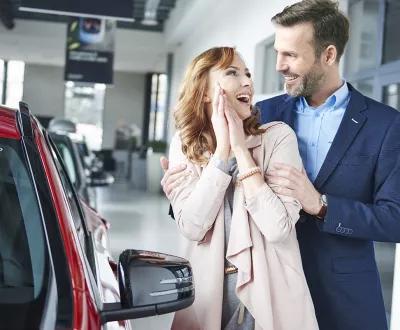 Femme avec son mari et heureuse de leur nouvelle voiture