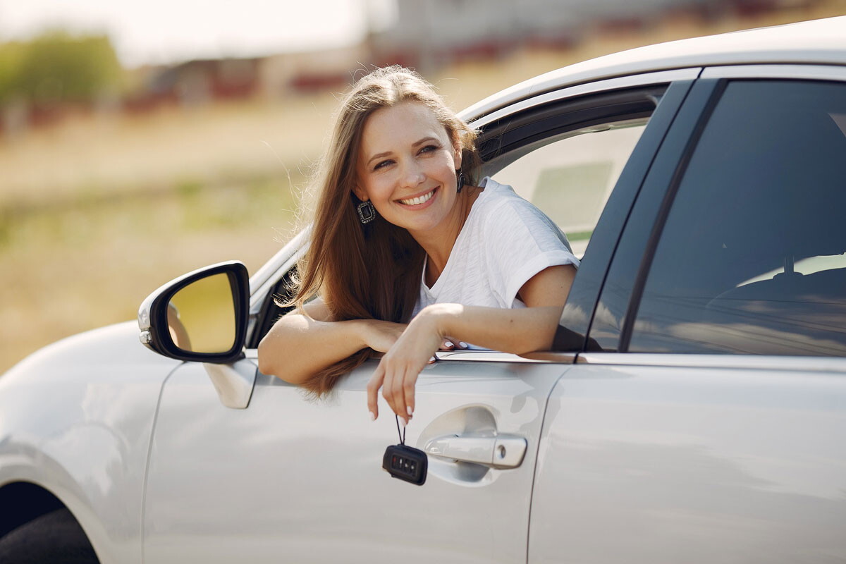 Femme heureuse passant la tête à travers la vitre de sa voiture