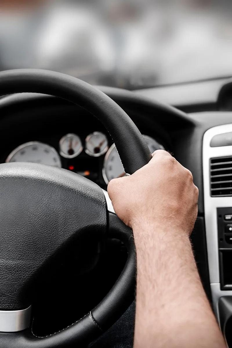 Main d'un conducteur tenant le volant de sa voiture